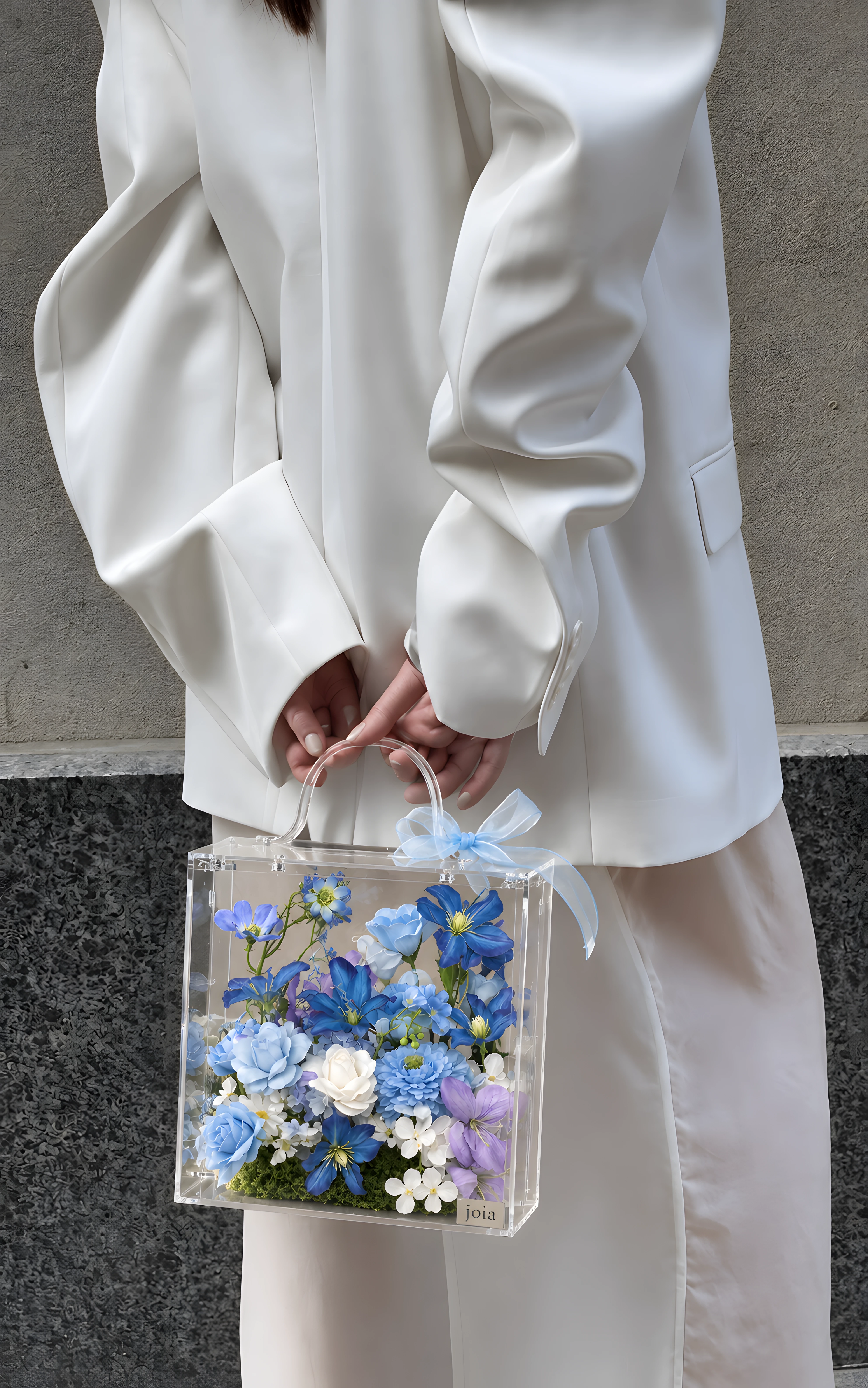 Woman in white carrying a blue JOIA flower valise